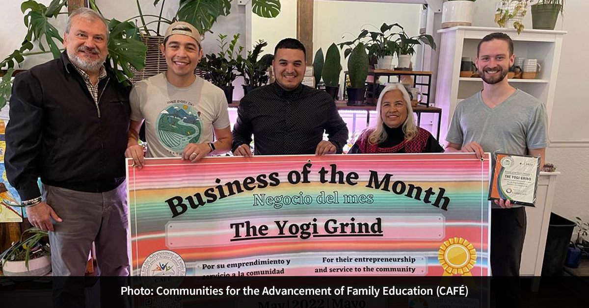 Five people holding a colorful sign with the text “Business of the Month, Negocio del mes, The Yogi Grind.”