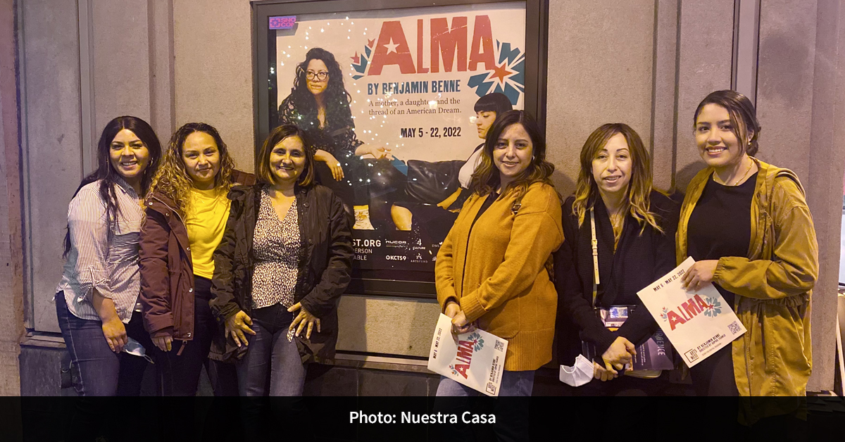 Six people standing in front of a poster for the play “Alma.”