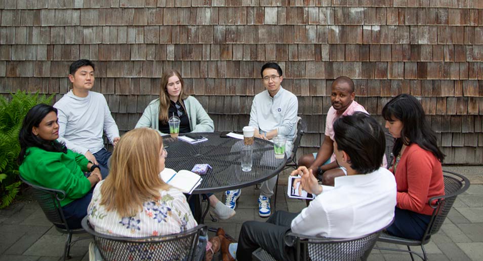 A group of people meeting around a table outdoors.