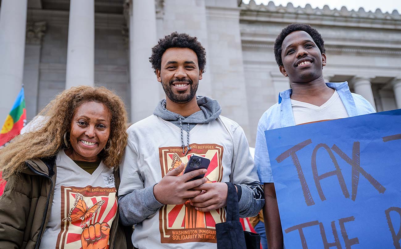 Three people posing for a photo in front of the Washington State Capitol Building.