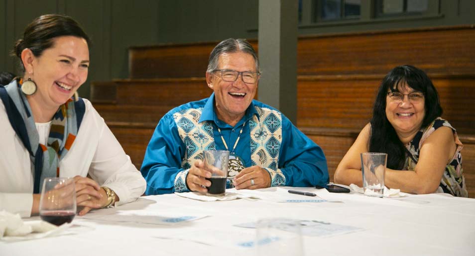  Three people sitting at a table, laughing.