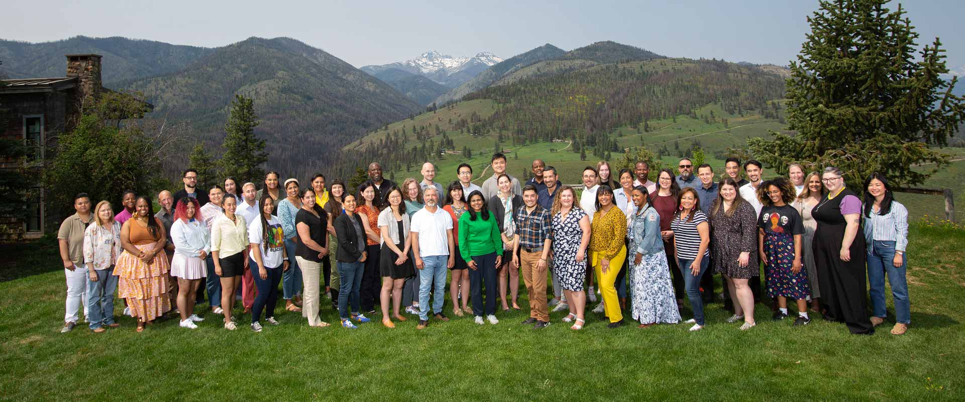 A group of more than 50 people pose outdoors with the backdrop of the Cascades mountain range behind them.