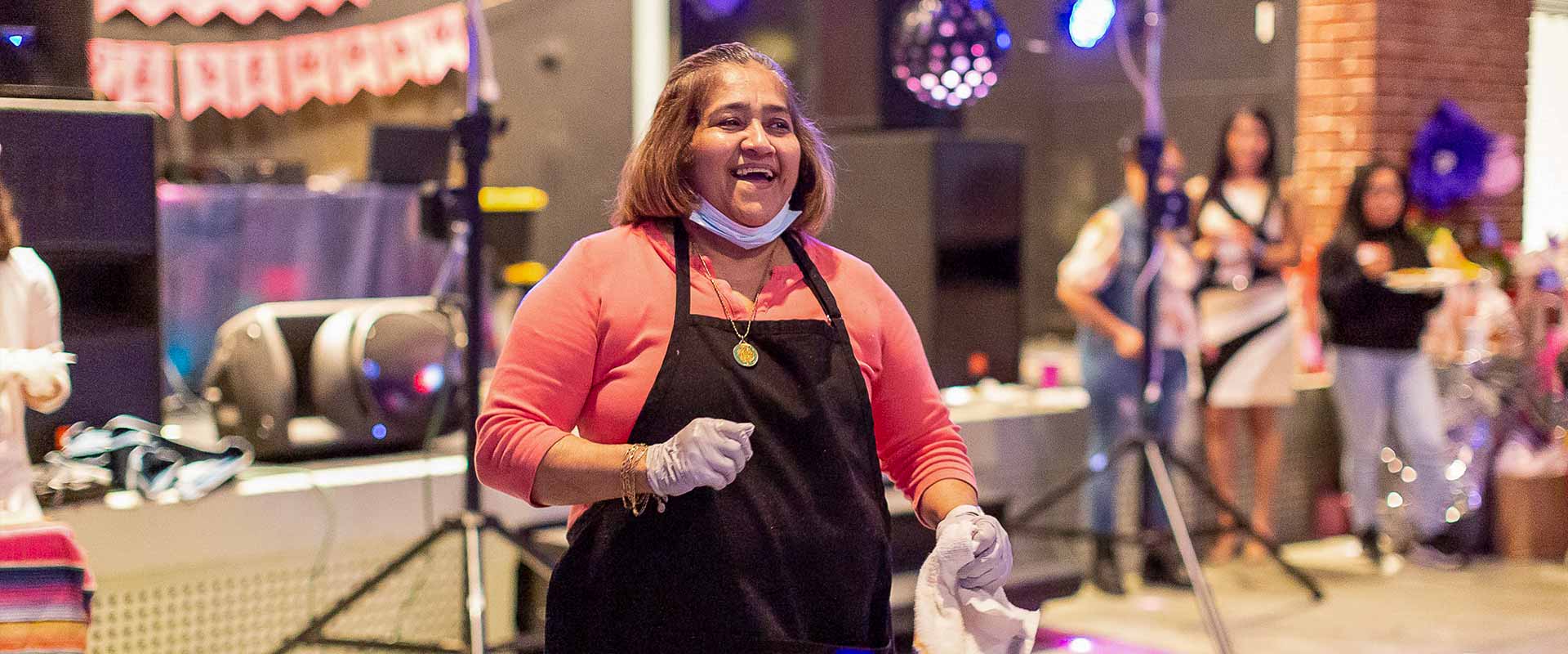 [Sponsorships] A person wearing food service gloves laughs on the floor of a community party