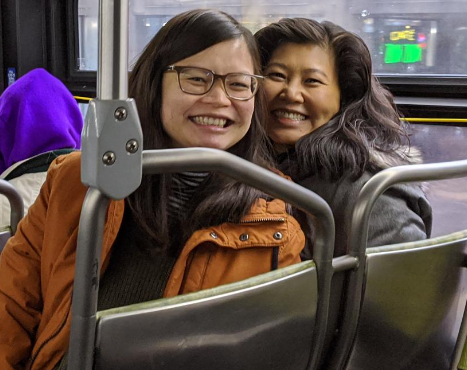 Two women sitting next to each other inside a bus.
