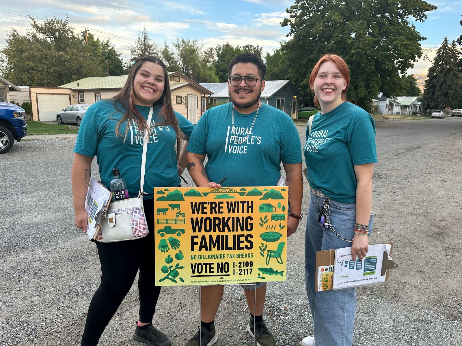 Rural People's Voice team members pose with a Vote No yard sign in Omak.